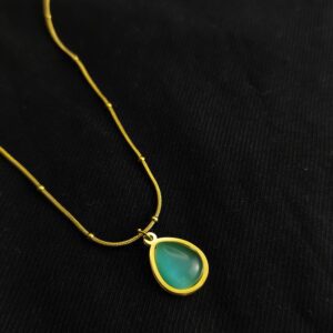 Emerald green teardrop pendant necklace with gold plated chain on black background