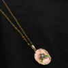 Blush pink enamel floral pendant necklace with gold plated chain on black background