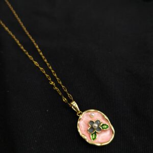 Blush pink enamel floral pendant necklace with gold plated chain on black background