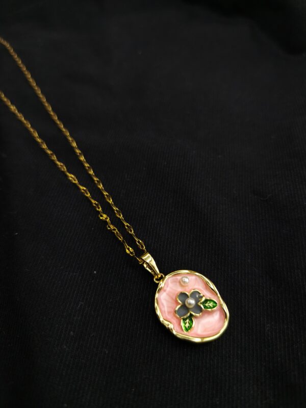 Blush pink enamel floral pendant necklace with gold plated chain on black background